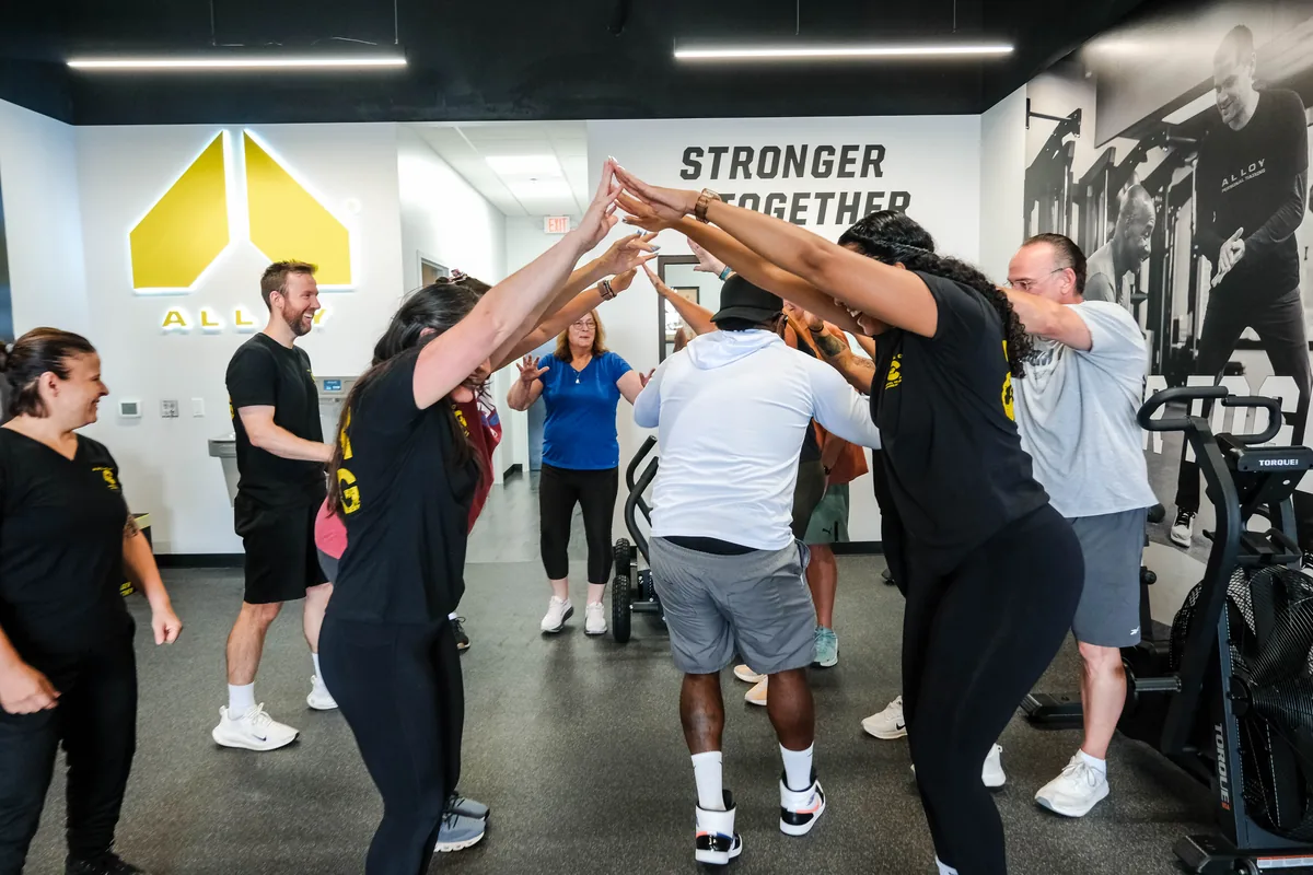 Members form a high-five tunnel at Alloy Personal Training Colorado Springs